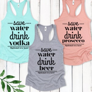 May include: Three tank tops with the text "Save water, drink [drink name]" on them. The tank tops are in different colors: light blue, gray, and peach. The text is in black and has a retro font. The text on the light blue tank top says "Save water, drink vodka". The text on the gray tank top says "Save water, drink beer". The text on the peach tank top says "Save water, drink prosecco".