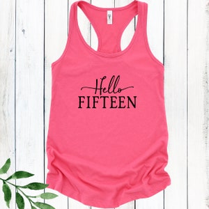 May include: Pink racerback tank top with black text that reads "Hello FIFTEEN".