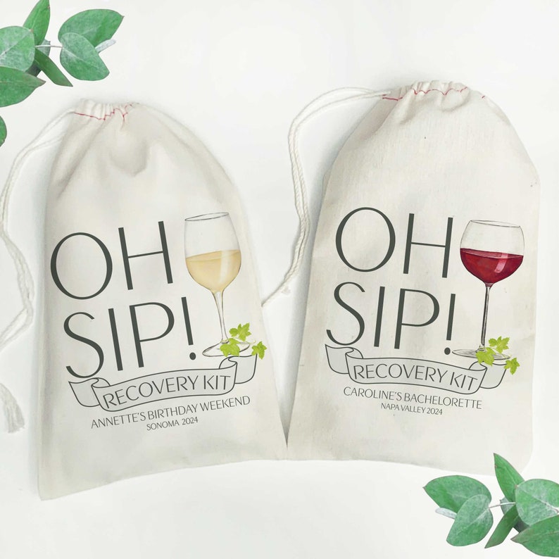 May include: Two white cotton drawstring bags with the text "OH SIP! RECOVERY KIT" printed on them. The bag on the left has a glass of white wine and the text "ANNETTE'S BIRTHDAY WEEKEND SONOMA 2024". The bag on the right has a glass of red wine and the text "CAROLINE'S BACHELORETTE NAPA VALLEY 2024".