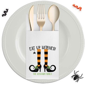 May include: A white paper cutlery holder featuring the text EAT UP WITCHES! and an illustration of orange and black striped stockings with black curled shoes. A gold knife, fork, and spoon are tucked inside. The holder is personalized with THE BECKHAM FAMILY.