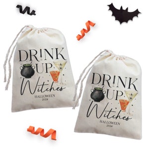 May include: Two white fabric drawstring bags with black text that reads "Drink Up Witches Halloween 2024". Each bag features a black cauldron, a green potion, and a cocktail glass with a red drink and an eyeball.