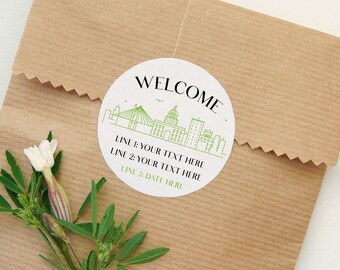 May include: A white round sticker with a green city skyline and the text "WELCOME" in black. The sticker also includes the text "LINE 1: YOUR TEXT HERE", "LINE 2: YOUR TEXT HERE", and "LINE 3: DATE HERE".