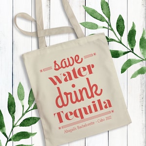 May include: A white canvas tote bag with red text that reads "save water drink tequila" and "Abagails Bachelorette - Cabo 2022".