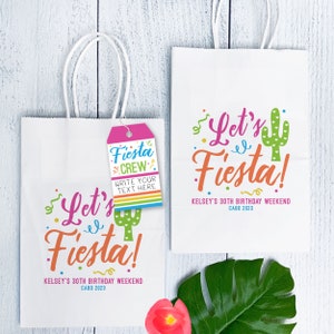 K&ouml;nnte beinhalten: Zwei wei&szlig;e Papiert&uuml;ten mit Henkeln. Die Taschen haben ein farbenfrohes Design mit dem Text "Let's Fiesta!" und "Kelsey's 30th Birthday Weekend Cabo 2023". Eine Tasche hat ein rosa Etikett mit dem Text "Fiesta Crew" und "Write your text here".