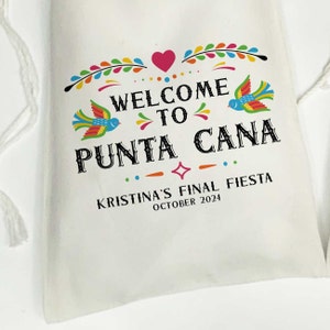 May include: White drawstring bag with a colorful welcome to Punta Cana design. The bag features a heart, birds, and floral accents. The text "Kristina's Final Fiesta October 2024" is printed below the design.