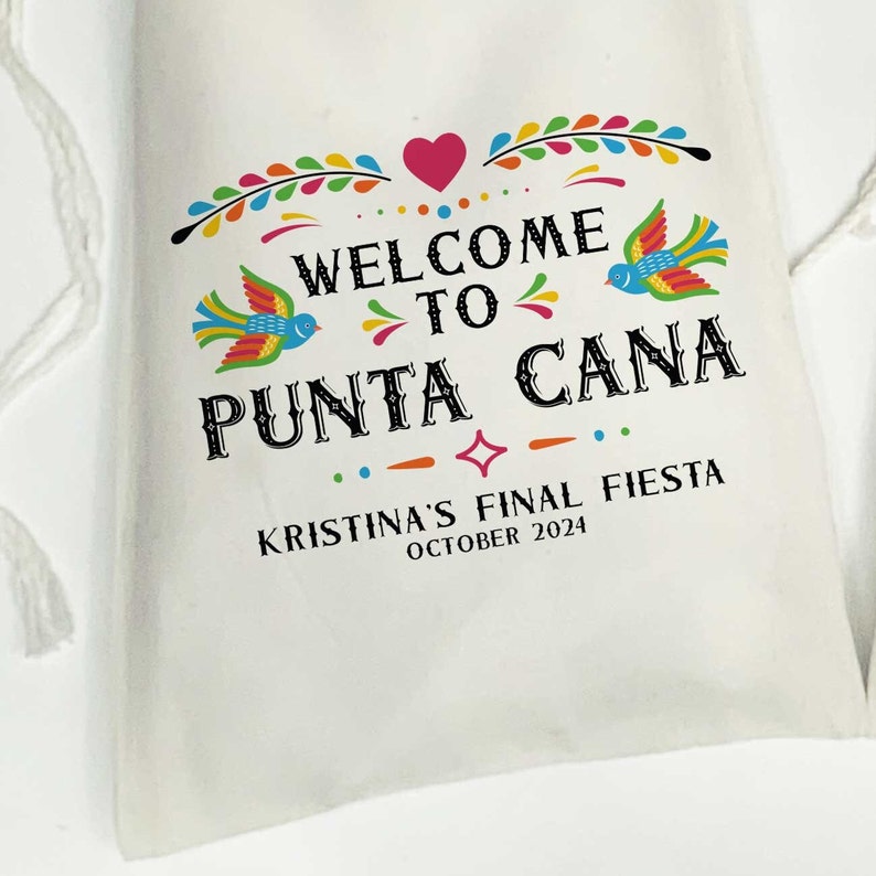 May include: White drawstring bag with a colorful welcome to Punta Cana design. The bag features a heart, birds, and floral accents. The text "Kristina's Final Fiesta October 2024" is printed below the design.
