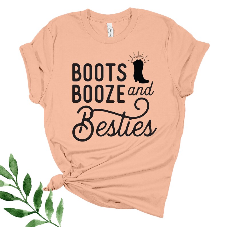 May include: Peach colored t-shirt with the text "Boots Booze and Besties" in black lettering. A black silhouette of a cowboy boot is next to the word "Boots".