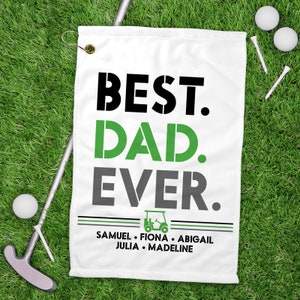 May include: White golf towel with black, green, and gray text that reads "Best Dad Ever."  A golf cart icon is below the text, and the names "Samuel, Fiona, Abigail, Julia, Madeline" are listed below the icon.