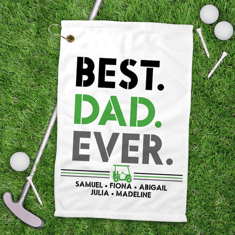 May include: White golf towel with black, green, and gray text that reads "Best Dad Ever."  A golf cart icon is below the text, and the names "Samuel, Fiona, Abigail, Julia, Madeline" are listed below the icon.