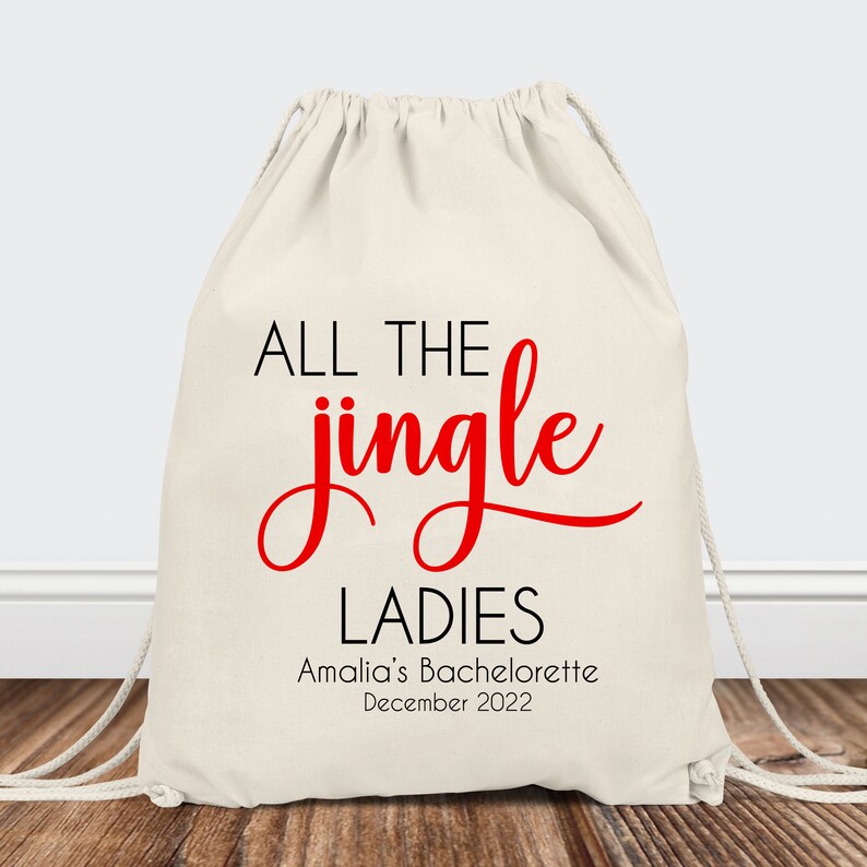May include: White drawstring bag with the text "ALL THE jingle LADIES" in black and red. The text "Amalia's Bachelorette December 2022" is printed below in black.