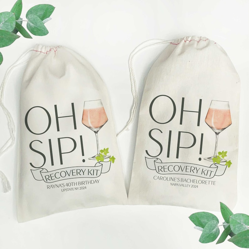 May include: Two white fabric drawstring bags with the text "Oh Sip! Recovery Kit" printed on them. The bag on the left says "Rayna's 40th Birthday, Upstate NY 2024". The bag on the right says "Caroline's Bachelorette, Napa Valley 2024". Both bags feature a glass of rose wine and green leaves.