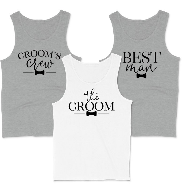May include: Three tank tops with different text and a bow tie graphic. The tank tops are gray and white. The text on the tank tops reads "Groom's Crew", "The Groom", and "Best Man".