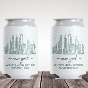 May include: Two white can coolers with a green New York City skyline design. The text "new york" is written in cursive, with the text "JAILENE'S 40TH BIRTHDAY NOVEMBER 2025" below it.
