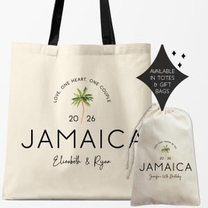 May include: Cream-colored tote bag and drawstring gift bag with "JAMAICA" printed in black. The tote bag has black handles and a palm tree graphic. Text includes "Love, One Heart, One Couple" and names. The gift bag says "Everything Gonna Be Ire".