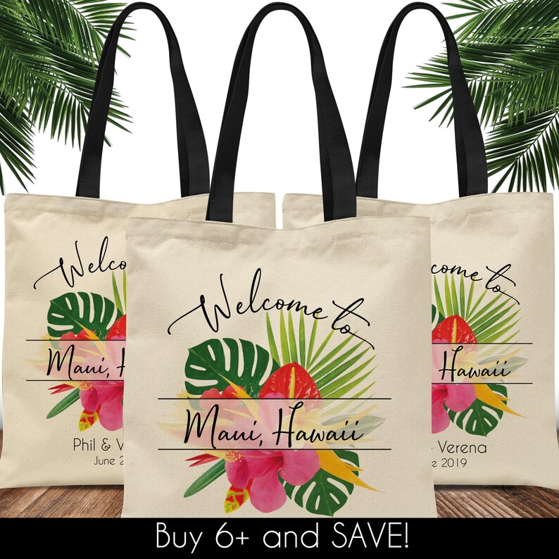 May include: Three white canvas tote bags with black handles. The center bag has a tropical floral design with the text "Welcome to Maui, Hawaii". The left bag has the text "Welcome to Maui, Hawaii" and the right bag has the text "Come to Hawaii".