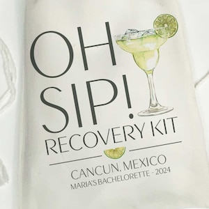 Op de afbeelding: Een witte tas met de tekst "Oh Sip! Recovery Kit" en een illustratie van een margarita-glas en een groene limoenwig. De tekst "Cancun, Mexico" en "Maria's Bachelorette - 2024" is ook inbegrepen.