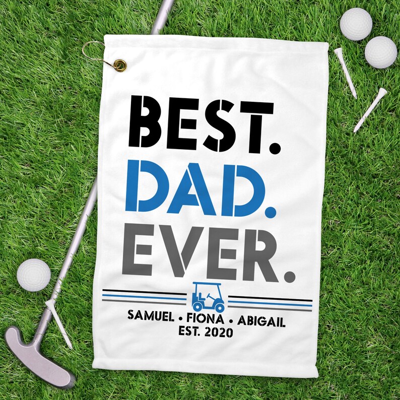 May include: White golf towel with the text "BEST. DAD. EVER." in black, blue, and gray lettering. Below the text is a small golf cart icon and the text "SAMUEL. FIONA. ABIGAIL EST. 2020" in black lettering.