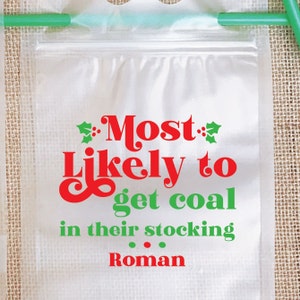 May include: A clear plastic bag with a red and green design that says "Most Likely to get coal in their stocking Roman".