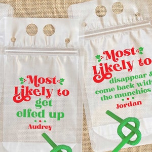 May include: Two clear plastic juice pouches with red and green text that reads "Most Likely to get elfed up... Audrey" and "Most Likely to disappear & come back with the munchies... Jordan".