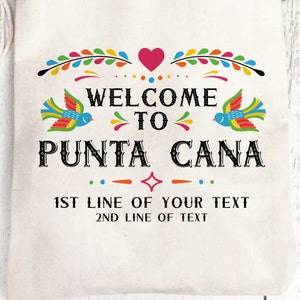 May include: A white canvas tote bag with a colorful welcome to Punta Cana design. The design features a heart, birds, and a floral border. The text "1st line of your text" and "2nd line of text" is below the design.