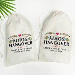 May include: Two white drawstring bags with colorful Mexican-style designs. The bags have the text "Adios Hangover" printed on them. One bag says "Hailey's 40th Fiesta Riviera Maya 2024" and the other says "Laura's Bachelorette Cancun 2024".