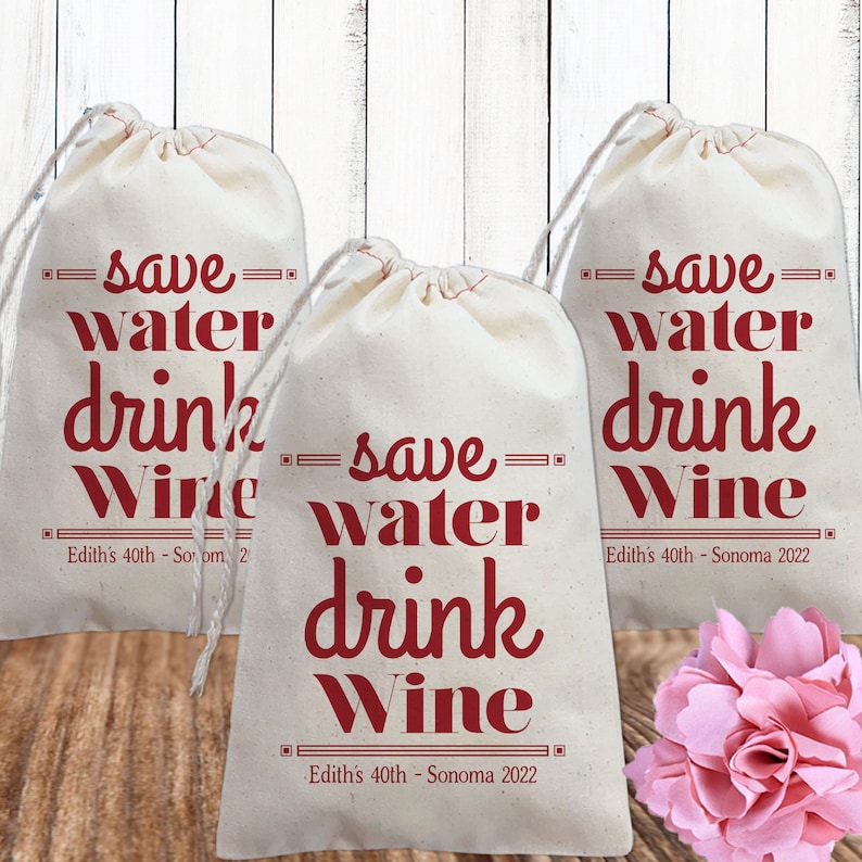 May include: Three white cotton drawstring bags with the text "save water drink wine" in red. The bags have the text "Edith's 40th - Sonoma 2022" printed on the bottom.