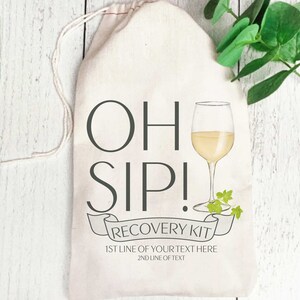 May include: White canvas bag with a drawstring closure. The bag has a graphic of a wine glass with the text "OH SIP! RECOVERY KIT" and "1ST LINE OF YOUR TEXT HERE 2ND LINE OF TEXT".