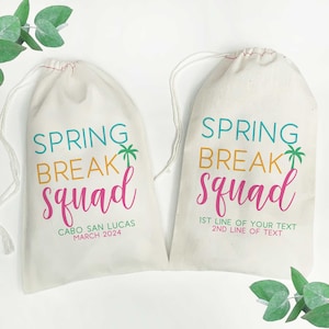 May include: Two white drawstring bags with the text "Spring Break Squad" printed on them. One bag has the text "Cabo San Lucas March 2024" printed below the main text. The other bag has the text "1st line of your text 2nd line of text" printed below the main text.