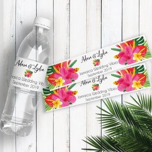 Puede incluir: Dos etiquetas de botella de agua con tem&aacute;tica tropical con el texto "Adam & Lydia" y "Jamaica Wedding Vibes September 2019". Las etiquetas presentan flores de hibisco rosas, hojas verdes y detalles amarillos.