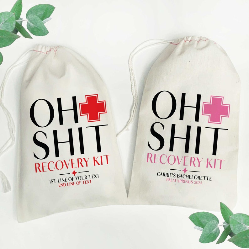 May include: Two off-white drawstring pouches made of fabric. The left bag features black text reading OH SHIT, a red medical cross, and red text reading RECOVERY KIT. The right bag has black text reading OH SHIT, a pink cross, and pink text reading RECOVERY KIT.
