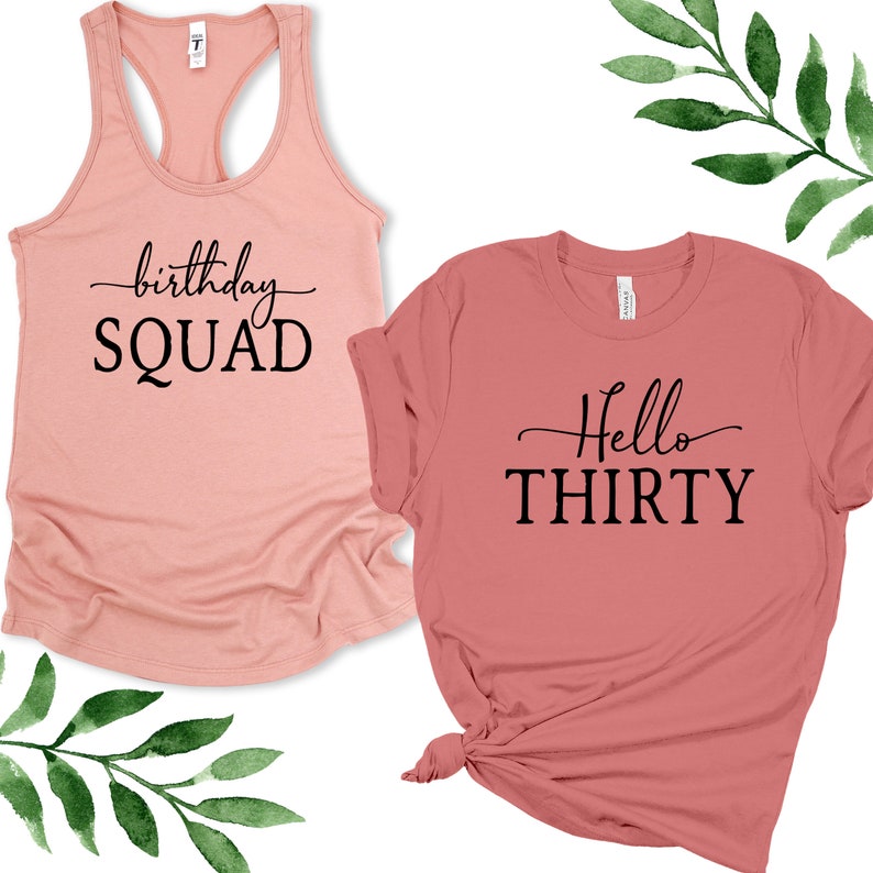May include: Two pink t-shirts with black text. One shirt says "birthday SQUAD" and the other says "Hello THIRTY".
