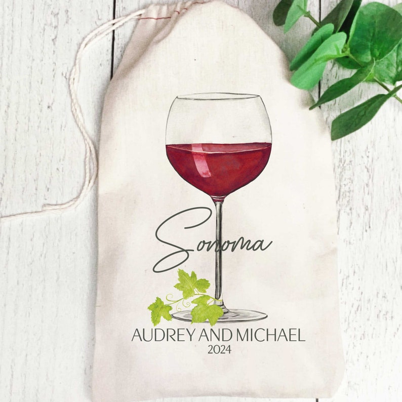 May include: A white canvas wine bag with a red wine glass illustration and the text "Sonoma" in cursive. The bag also includes the text "Audrey and Michael 2024".