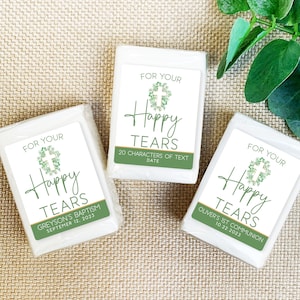 May include: Three white tissue boxes with green and gold labels that say "For Your Happy Tears". The labels also include a cross with green leaves and a date. The first label says "Greyson's Baptism September 12, 2023". The second label says "20 Characters of Text Date". The third label says "Oliver's 1st Communion 10.22.2023".
