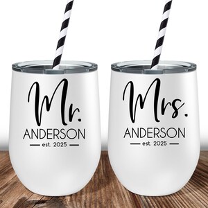 Puede incluir: Dos vasos blancos de acero inoxidable con pajitas negras. El vaso de la izquierda dice "Mr. Anderson - est. 2025" y el vaso de la derecha dice "Mrs. Anderson - est. 2025".