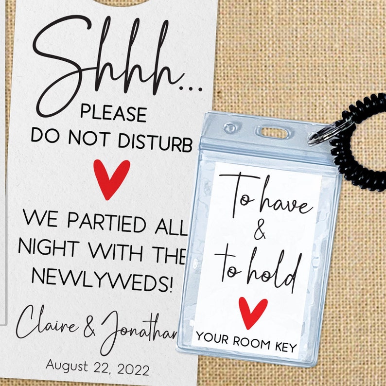 May include: A white card with the text "Shhh... Please Do Not Disturb" and a red heart. Below the text is "We partied all night with the newlyweds!" and the names "Claire & Jonathan" and the date "August 22, 2022". A clear plastic card holder with a black lanyard attached to it has the text "To have & to hold" and a red heart. Below the text is "Your Room Key".