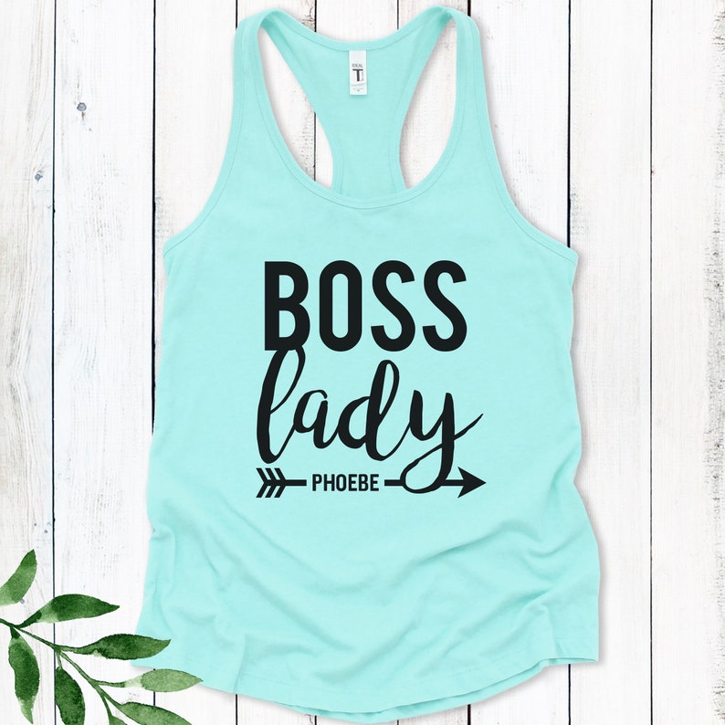 May include: A turquoise tank top with the text "BOSS lady" in black lettering and an arrow with the word "PHOEBE" underneath.