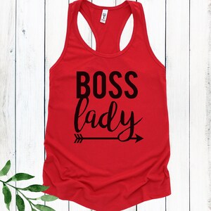 May include: Red racerback tank top with black text that reads "BOSS lady" and a black arrow pointing to the right.
