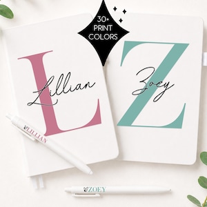 May include: Two white notebooks and two white pens. One notebook features a large pink letter L with the name Lillian in black script. The other notebook has a large teal letter Z with the name Zoey in black script. Text reads 30+ PRINT COLORS.