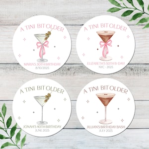 May include: Four round white stickers with pink and gold accents. Each sticker features a martini glass with a pink ribbon and the text "A Tini Bit Older". Each sticker has a personalized birthday message.