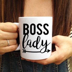 May include: White ceramic mug with a black arrow and the text "BOSS lady" in black lettering.