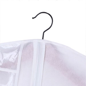 May include: White garment bag with a zipper closure and a clear plastic window. The bag has a black metal hanger.