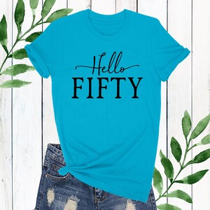 May include: A turquoise blue t-shirt with the text "Hello Fifty" in black lettering.