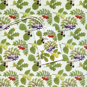 May include: A gift tag with a white string, featuring a botanical illustration of green leaves, red berries, green apples, and purple berries. The background is a repeating pattern of the same botanical elements.