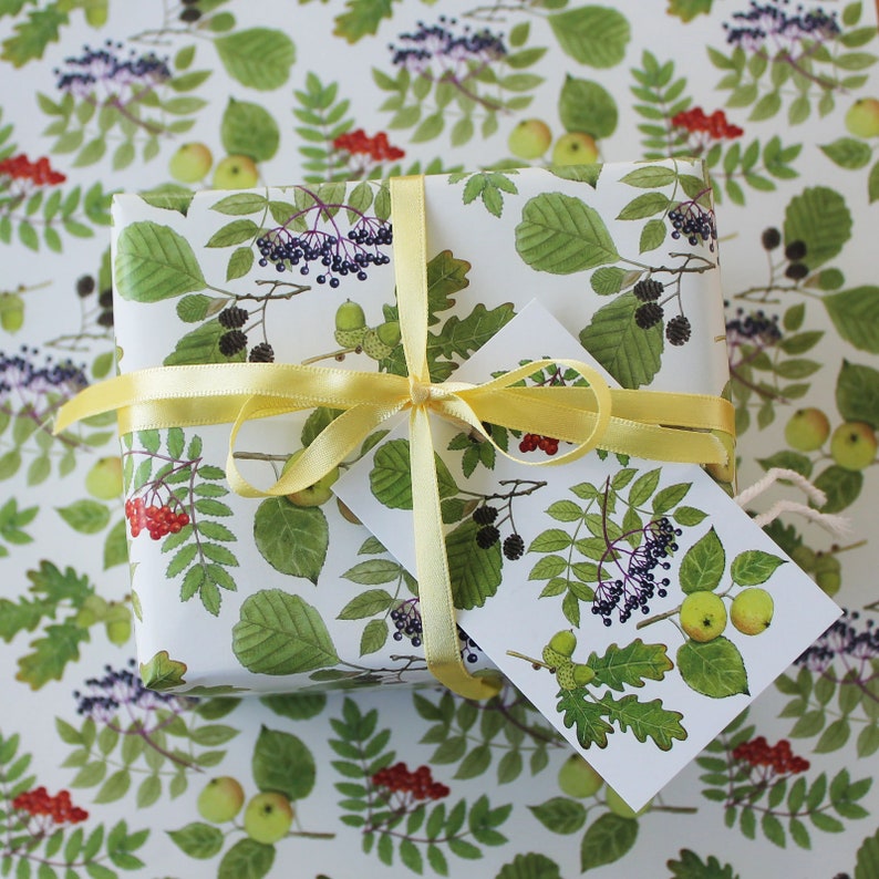 May include: A wrapped gift box with a botanical print of green leaves, red berries, and green apples. The gift is tied with a yellow ribbon and a matching gift tag. The background features the same botanical pattern.