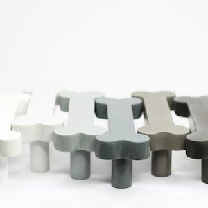 May include: Six bone-shaped cabinet knobs in various shades of grey, from white to dark grey.