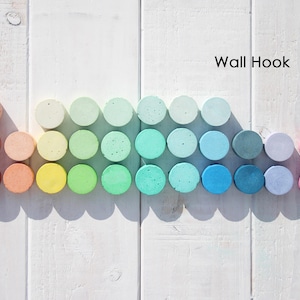 May include: A selection of circular wall hooks in a gradient of colours, from red to pink, displayed on a white wooden surface. The hooks are arranged in a row and include shades of orange, yellow, green, and blue. Text on the image reads "Wall Hook".