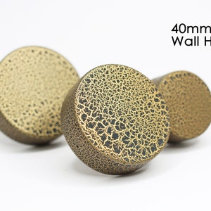 May include: Three gold-coloured wall hooks with a crackled finish. The hooks are 40mm in diameter.