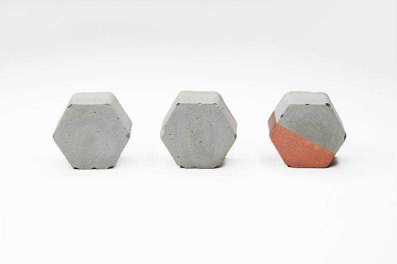 May include: Three hexagonal concrete objects. Two are grey and one is half grey and half copper.