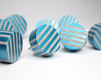 May include: A group of eight blue and white striped round cabinet knobs. The knobs are made of concrete and have a metallic finish.