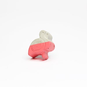 Könnte beinhalten: Eine kleine, rosafarbene und graue Beton-Flamingofigur.